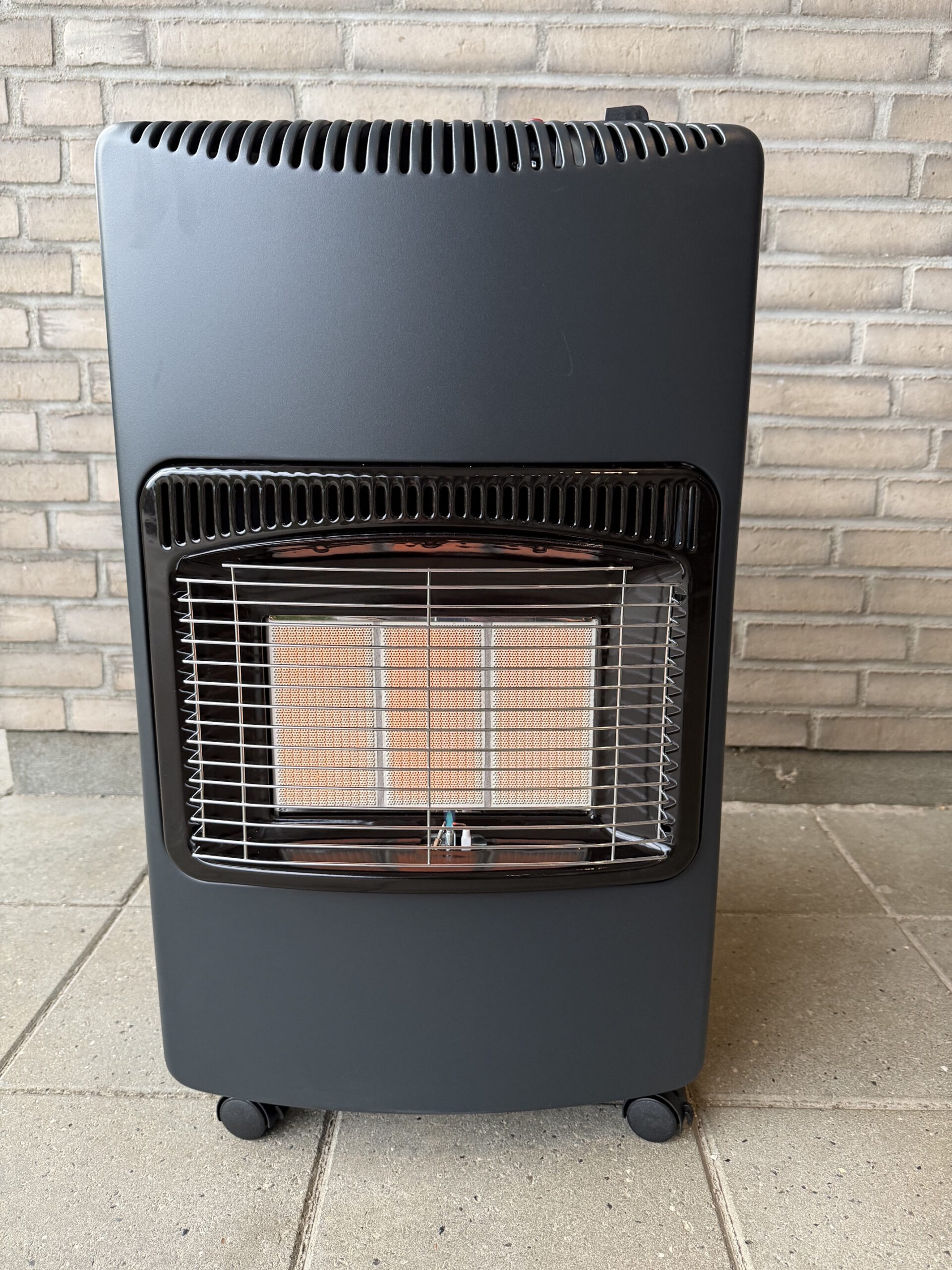 Tændt gasvarmeovn foran mur