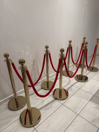 Messingstolper med røde bånd foran væg
